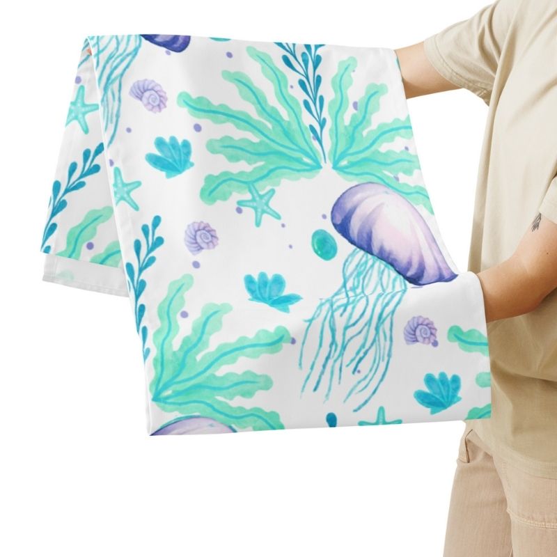 Person holding a coastal table runner with a colorful sea-themed pattern