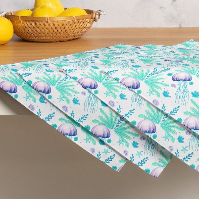 Seamless pattern of jellyfish and seaweed on a set of 4 beach placemats, on a table with lemons in a basket.