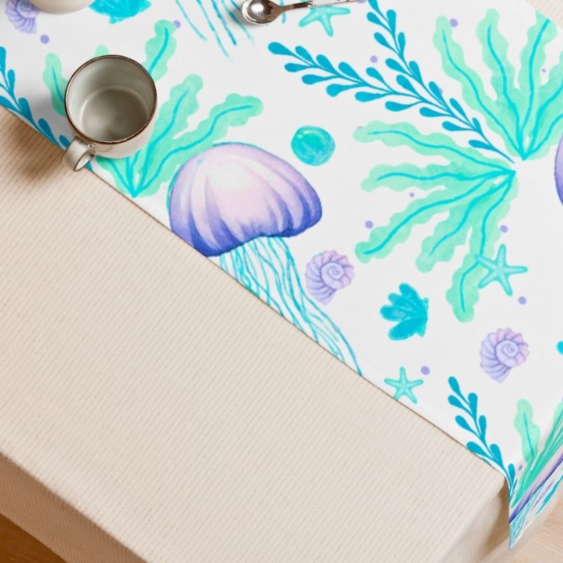 Beach house table runner with ocean-themed design featuring seashells and seaweed on a white background.