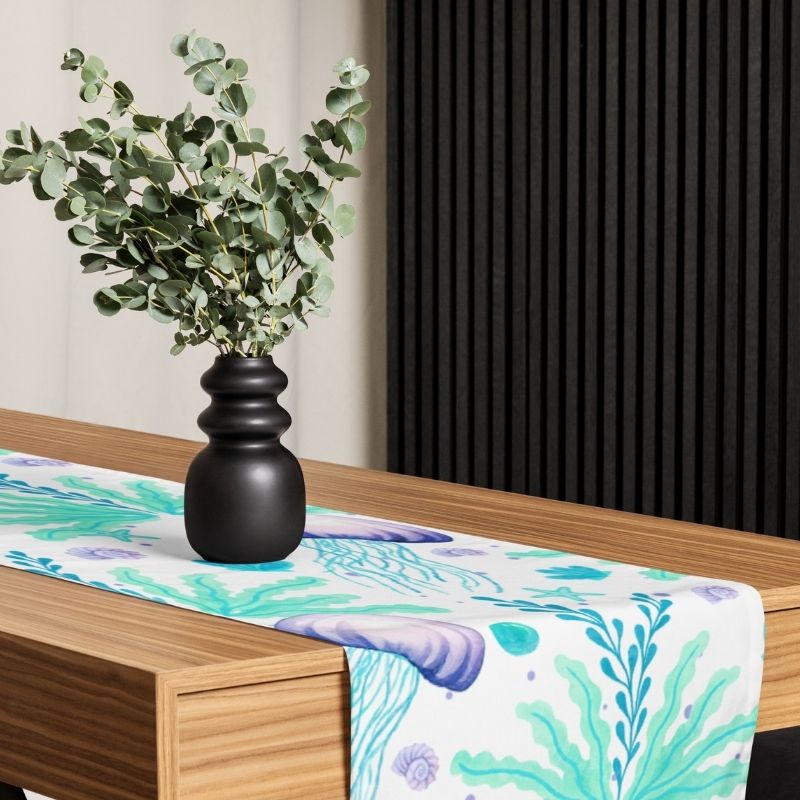 Black vase with greenery on a table with a colorful coastal table runner for a beach house