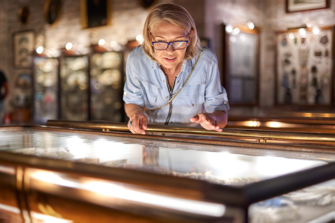 A lady museum visitor closely observing an encased exhibit at an art museum.