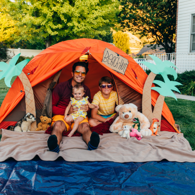 A dad and kids sitting in a tent that's decorated as a beach