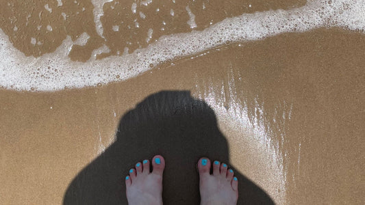 white bubbles of surf and two feet surrounded by a shadow of the person taking the picture form above