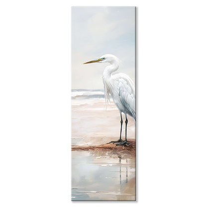 Heron wall art – a heron standing still in shallow water at the shoreline, canvas print