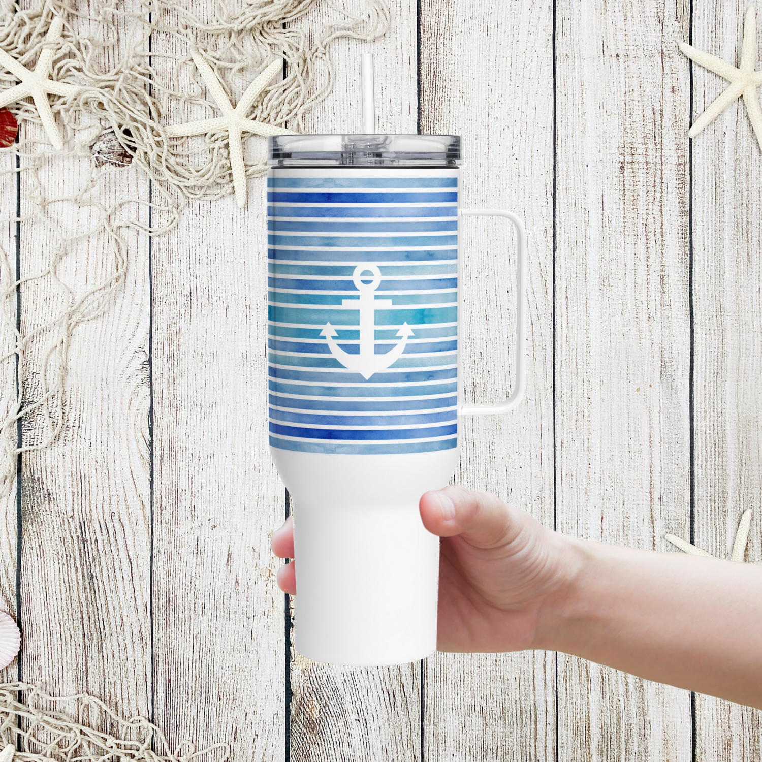 Hand holding a Coastal 40 oz tumbler with navy stripes and white anchor design, the best coastal travel coffee mug.