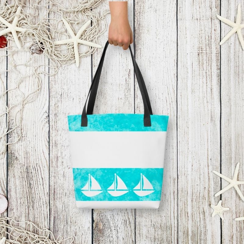 Styled flat-lay of the coastal tote held by hand, with whitewashed wood and starfish accents for a beachside vibe.

