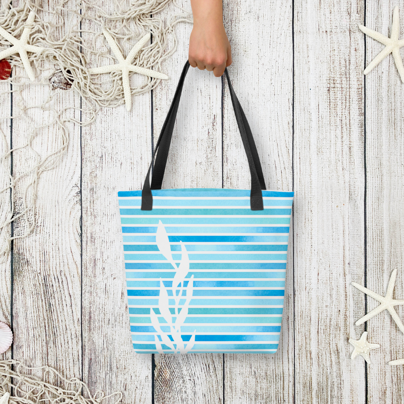 Styled flat-lay of the blue handbag held by hand, with whitewashed wood and starfish accents for a beachside vibe.
