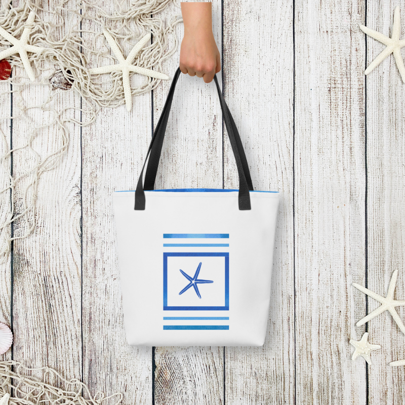 Styled flat-lay of the navy blue bag held by hand, with whitewashed wood and seashell accents for a beachside vibe.
