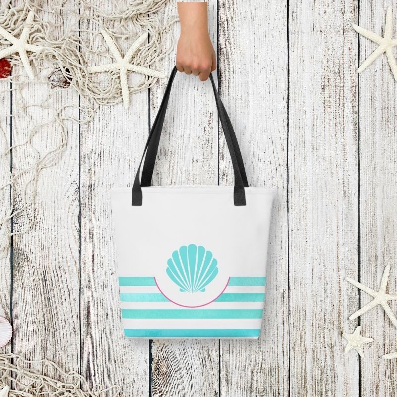 Styled flat-lay of the turquoise tote held by hand, with whitewashed wood and starfish accents for a beachside vibe.
