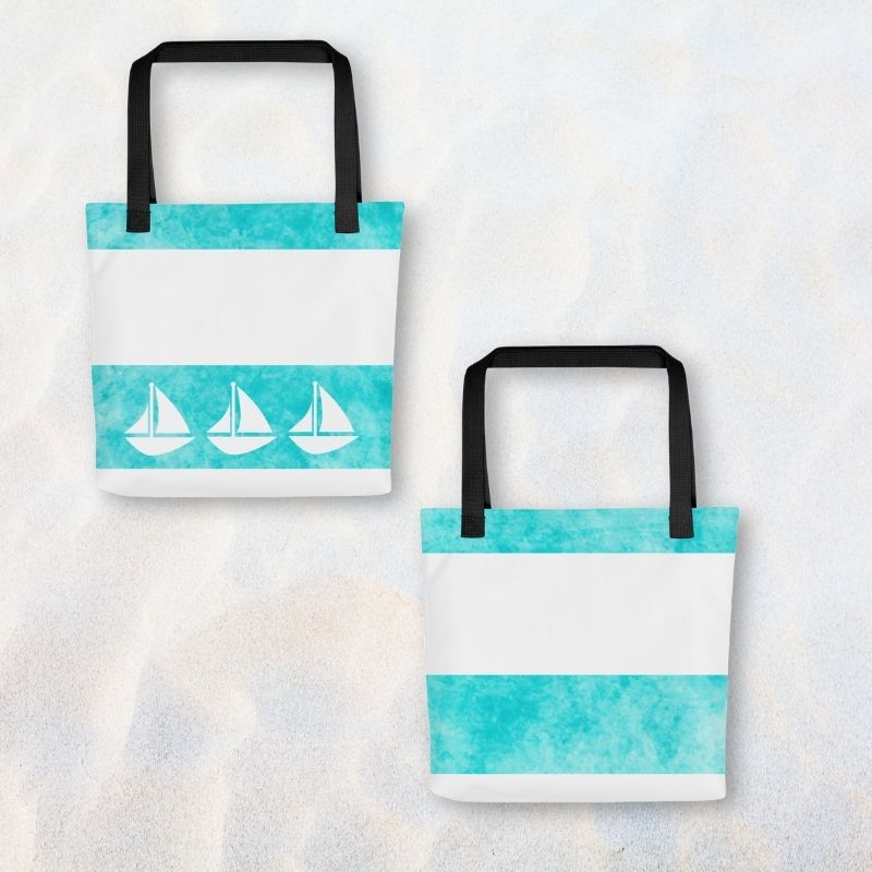 women tote bag shown front and back on sand, featuring nautical sailboat details and roomy 15” x 15” size.


