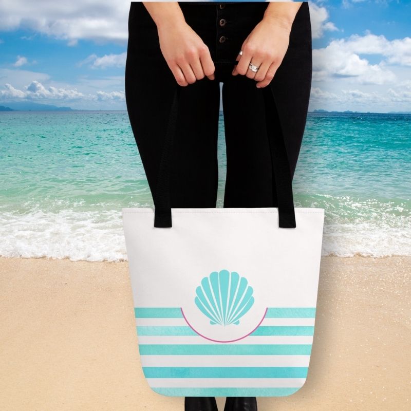 women holding coastal bag in front of a beach beach scene
