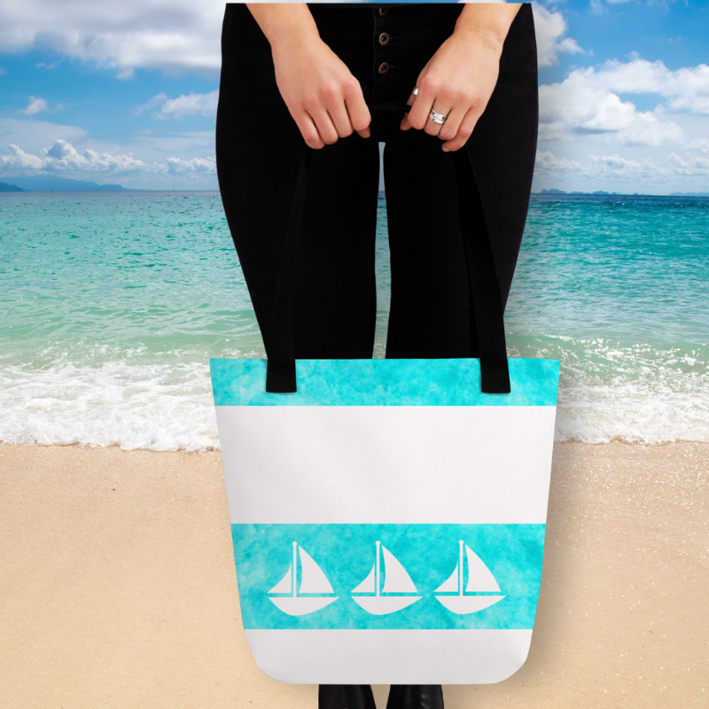 lady holding a teal tote bag in front of the beach