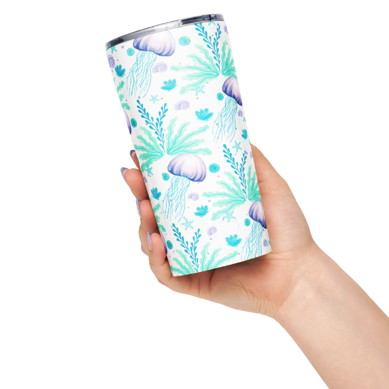 Hand holding an insulated coffee mug stainless steel with aqua and lavender jellyfish coastal pattern.
