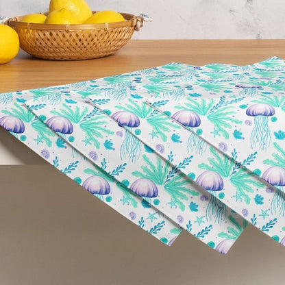 Seamless pattern of jellyfish and seaweed on a set of 4 beach placemats, on a table with lemons in a basket.