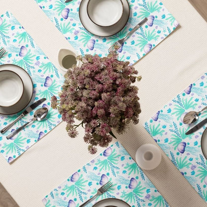 Table setting with floral centerpiece and ocean inspired coastal placemats with jellyfish and sea grasses