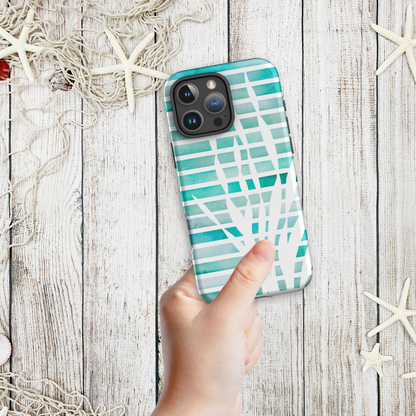 Hand holding a coastal phone case iPhone design with abstract teal kelp fronds layered over watercolor stripes, styled with a nautical net and starfish.